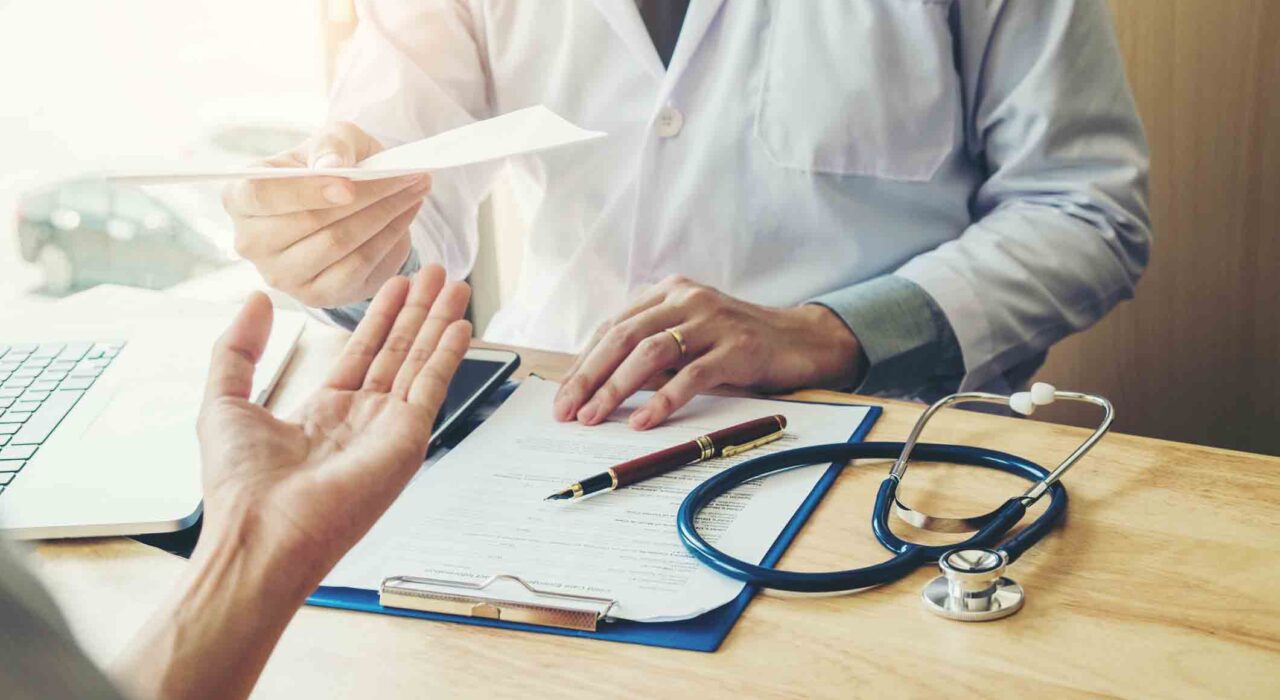 Doctor or physician writing diagnosis and giving a medical prescription to female Patient