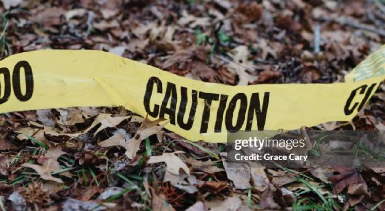 Close-up yellow caution tape on ground in wooded area