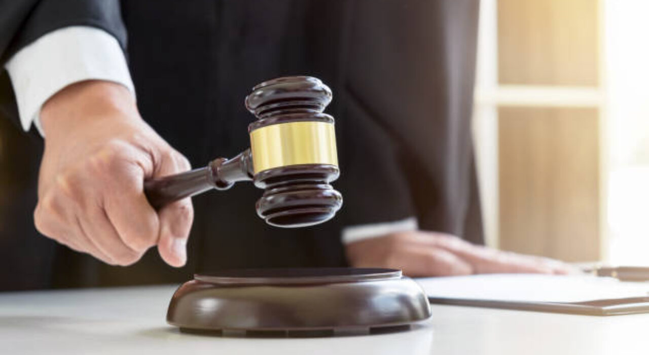Close up of Male lawyer or judge hand's striking the gavel on sounding block, working with Law books, report the case on table in modern office, Law and justice concept.