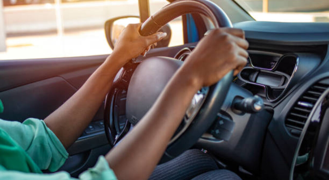 Side view of a woman sitting in a car holding a steering wheel and looking on the road. Young African American woman driving the car. Cropped shot of an unrecognizable woman driving her car